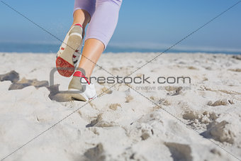 Sporty womans feet jogging on the sand