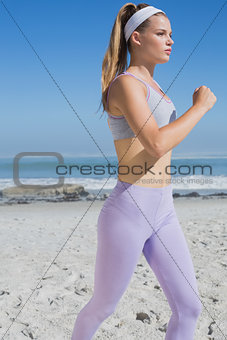 Sporty focused blonde jogging on the beach