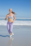 Sporty smiling blonde jogging on the beach