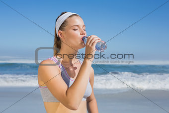 Sporty blonde drinking water on the beach