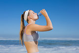 Sporty blonde drinking water on the beach