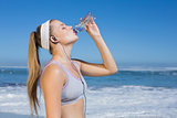 Sporty blonde on the beach drinking water