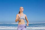 Sporty focused blonde jogging on the beach