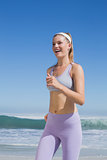 Sporty happy blonde jogging on the beach