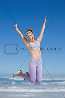 Sporty happy blonde jumping on the beach