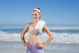 Sporty happy blonde standing on the beach with towel