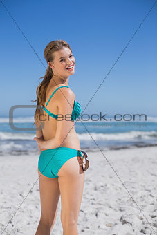 Fit woman in bikini on beach smiling at camera