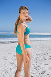 Fit woman in bikini on beach looking at camera