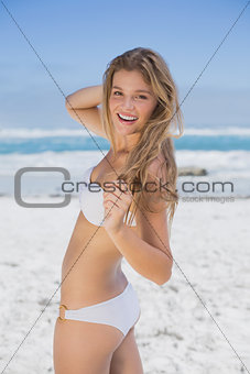 Beautiful happy blonde on the beach in white bikini