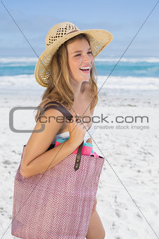 Beautiful laughing blonde on the beach holding bag