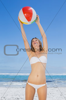 Smiling slim woman catching beach ball