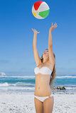 Smiling slim woman throwing beach ball
