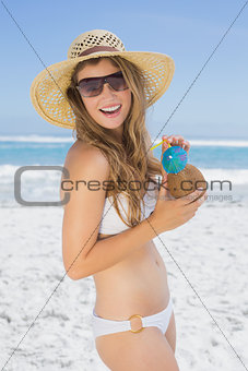 Pretty blonde in white bikini with coconut drink on the beach