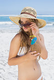 Pretty blonde in white bikini holding coconut drink on the beach