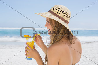 Pretty blonde in bikini holding cocktail on the beach