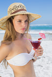 Pretty blonde holding cocktail on the beach