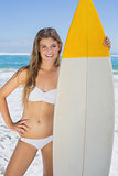 Pretty surfer girl holding her surfboard on the beach