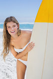 Pretty surfer girl holding her surfboard on the beach