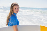 Fit happy surfer girl on the beach with her surfboard
