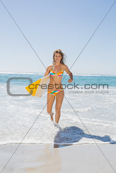 Beautiful surfer girl walking from the sea with her surfboard