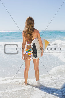 Fit surfer girl standing in the sea with her surfboard