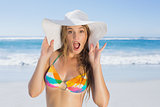 Beautiful girl in bikini and straw hat looking at camera on beach
