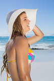 Beautiful girl in bikini and straw hat smiling on beach