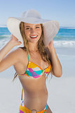 Beautiful girl in bikini and straw hat on the beach smiling at camera