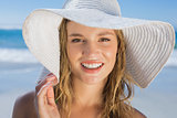 Beautiful girl in straw hat on the beach smiling at camera