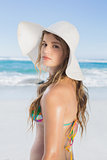Beautiful girl on the beach posing in white straw hat and bikini