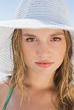Beautiful girl on the beach smiling in white straw hat and bikini