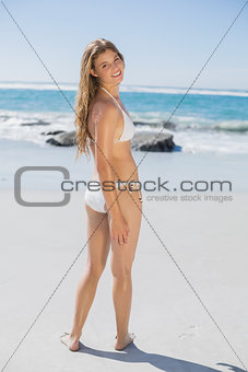 Smiling fit woman in white bikini on beach