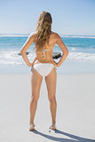 Fit woman in white bikini standing on beach