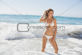 Beautiful smiling woman in white bikini standing in the sea
