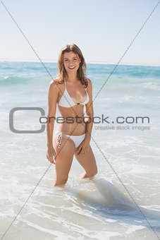 Beautiful smiling woman in white bikini standing in the sea
