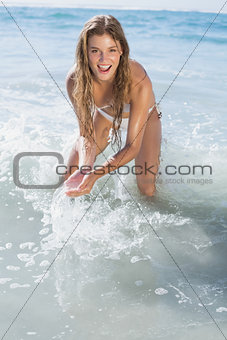 Beautiful smiling woman in white bikini splashing on the beach