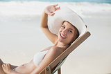 Smiling woman relaxing in deck chair on the beach