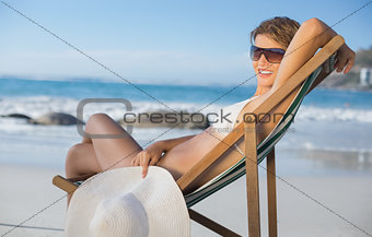 Pretty smiling woman relaxing in deck chair on the beach