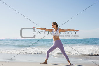 Sporty blonde in warrior pose on the beach