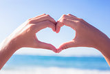 Hands making heart shape on the beach
