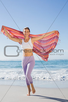 Sporty blonde standing on the beach with a scarf