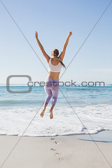 Sporty blonde jumping up on the beach