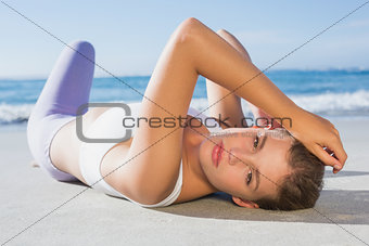 Sporty blonde lying on the beach looking at camera