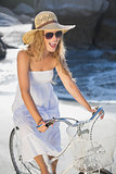 Beautiful smiling blonde in sundress on bike at the beach