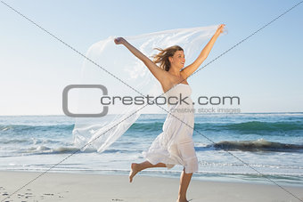 Beautiful smiling blonde in white sundress on the beach with scarf