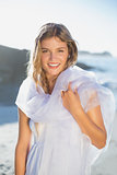 Beautiful smiling blonde in white sundress and scarf on the beach