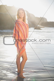 Beautiful happy blonde wrapped in scarf at the beach