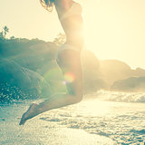 Beautiful jumping blonde in white bikini at the beach