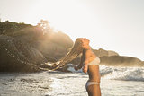 Beautiful blonde in white bikini at the beach tossing wet hair