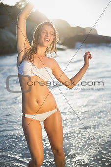 Beautiful laughing blonde in white bikini at the beach with wet hair